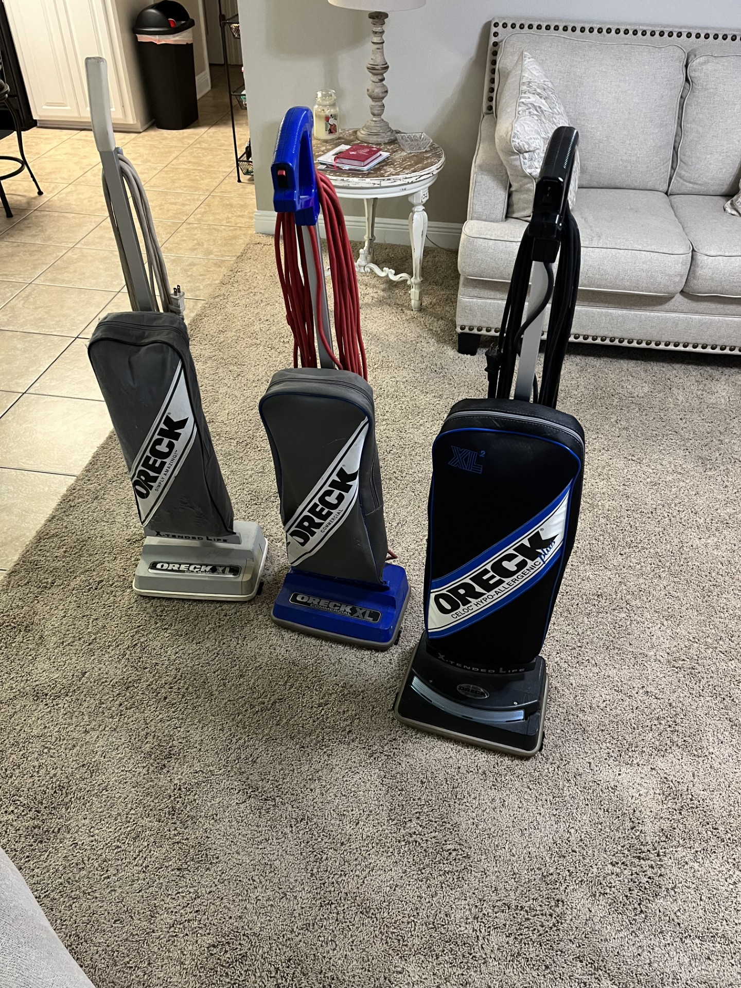 Three Oreck upright vacuum cleaners in gray, blue and black available for sale